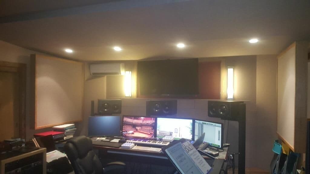 Modern music studio interior with dual monitors, keyboard, and professional audio equipment.