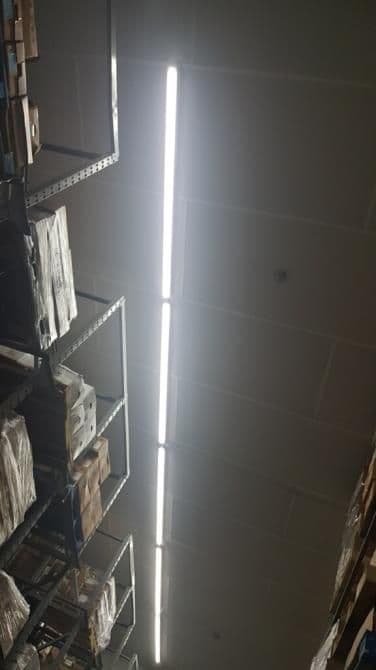 Bright overhead LED lights illuminate a storage area filled with stacked boxes on metal shelves.