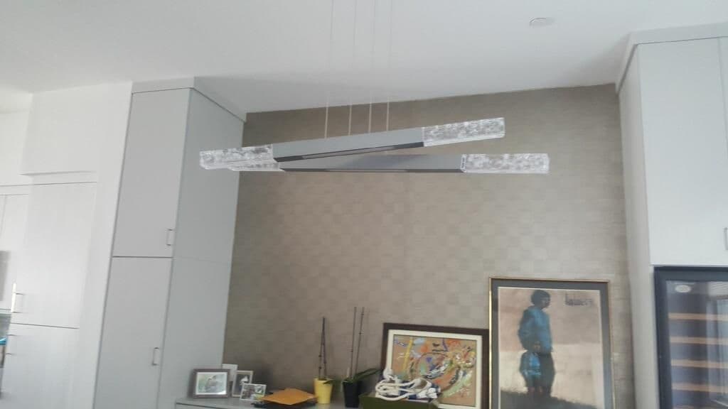 Modern pendant light fixture hanging in a stylish kitchen with decorative wall art.