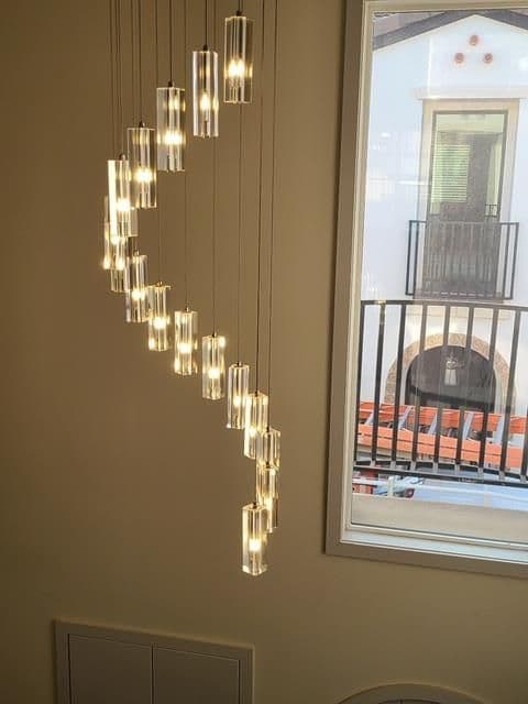 Modern pendant light fixture with hanging clear glass bulbs against a bright window.