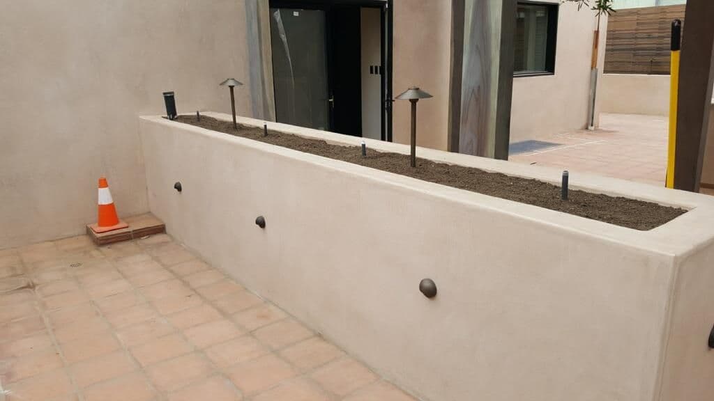 Raised garden bed with soil, outdoor lighting fixtures, and a traffic cone nearby.