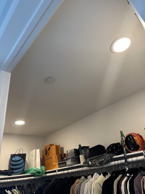 Brightly lit closet with shelves holding bags, hats, and clothing items.