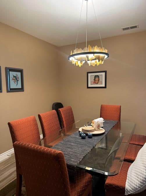 Modern dining room featuring a glass table, orange upholstered chairs, and decorative lighting.