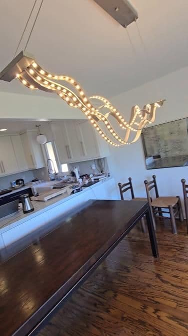 Modern dining room with a unique wavy pendant light and wooden dining table.