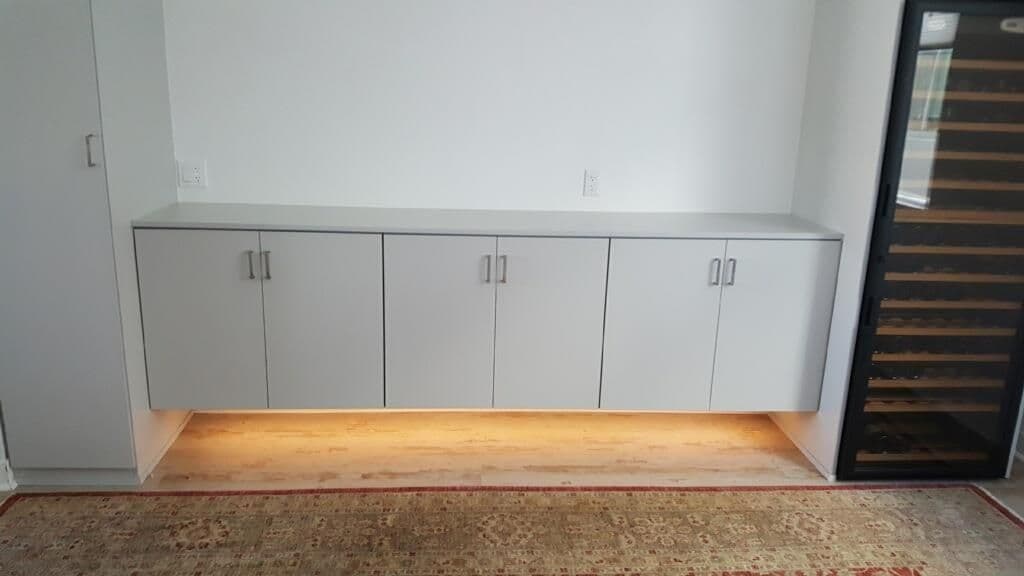 Modern gray cabinets with under-cabinet lighting in a minimalist room setting.