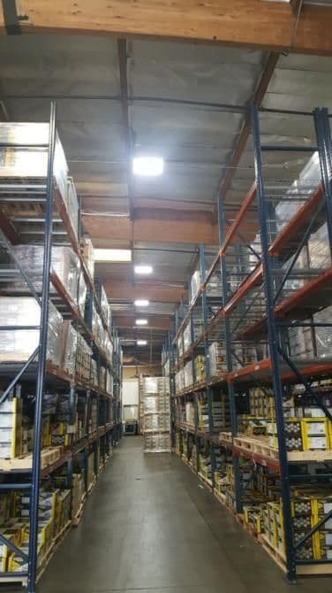 Interior of a warehouse with tall shelving units filled with boxed products, well-lit space.