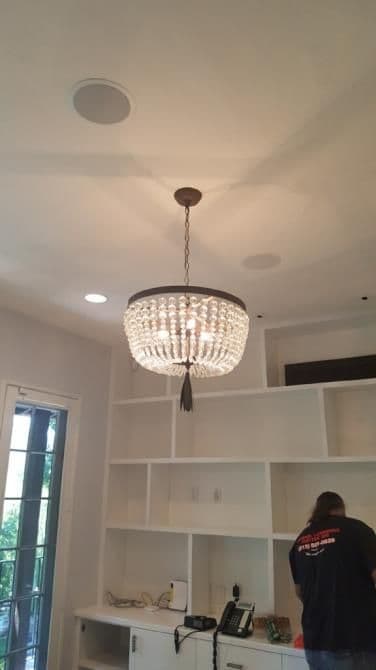 Elegant crystal chandelier hanging from the ceiling in a modern interior space.