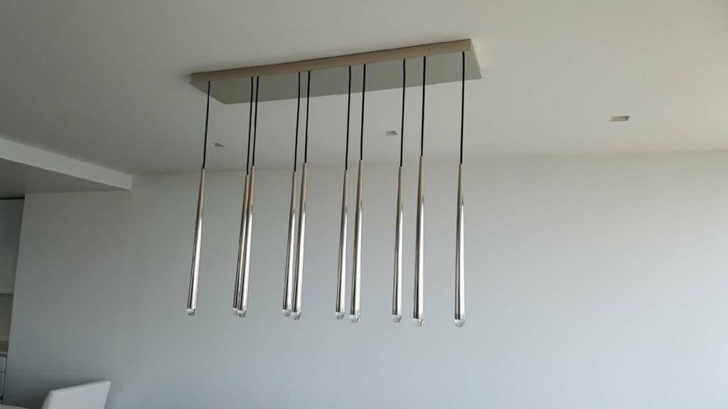 Modern pendant light fixture with seven sleek, elongated tubes hanging from a ceiling mount.