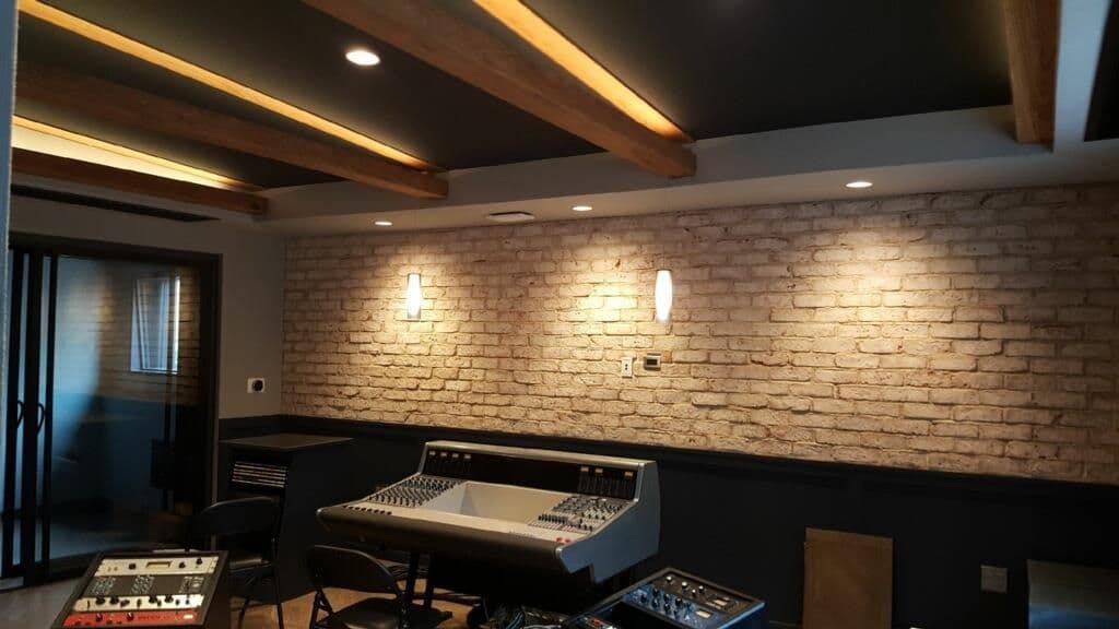 Modern music recording studio with brick walls, ambient lighting, and mixing console.