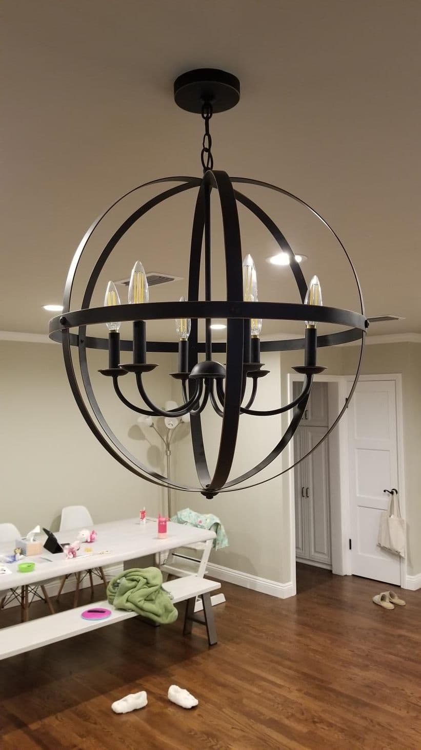 Modern globe chandelier with six lights, hanging in a contemporary dining space.