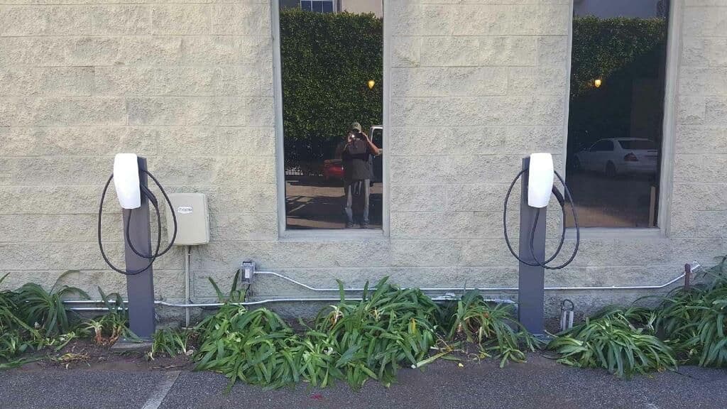 Electric vehicle charging stations next to building, reflecting surrounding greenery.
